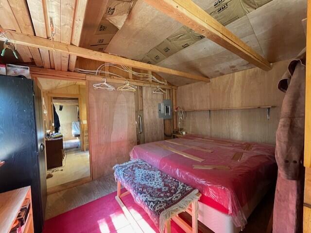 bedroom featuring wood walls and electric panel