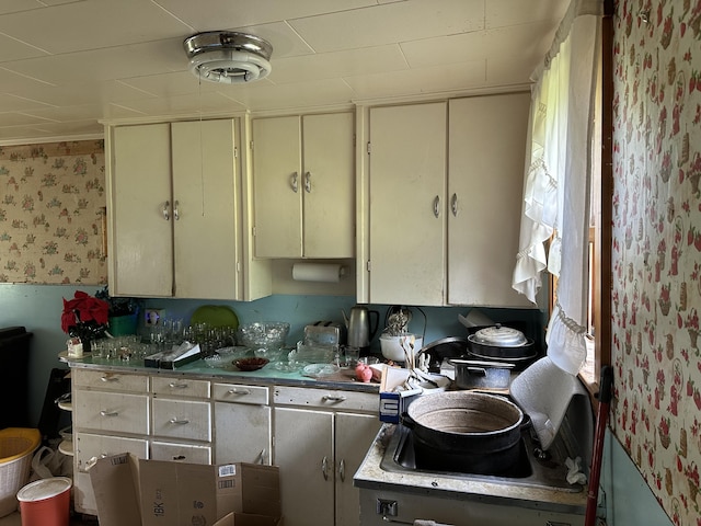 kitchen with cream cabinetry and wallpapered walls