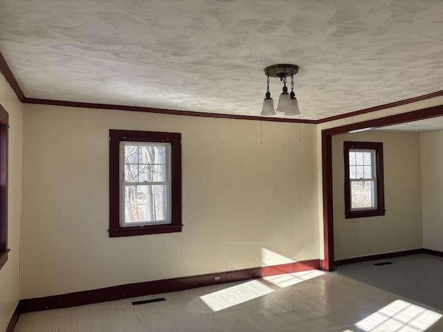 empty room with ornamental molding and a textured ceiling