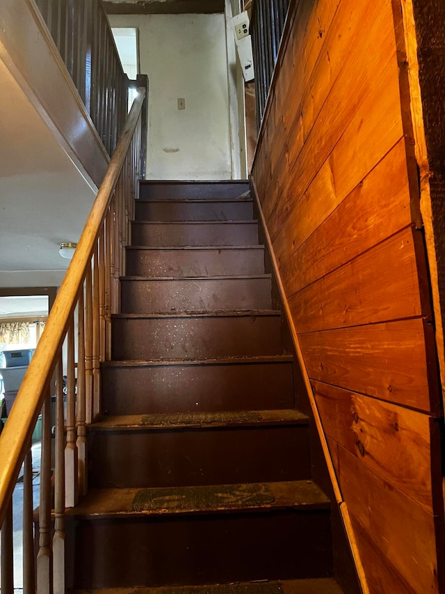 staircase featuring wooden walls