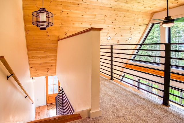 stairway featuring ceiling fan, wooden ceiling, wood walls, vaulted ceiling, and hardwood / wood-style flooring