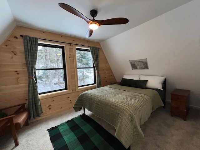 carpeted bedroom with lofted ceiling, ceiling fan, and wooden walls