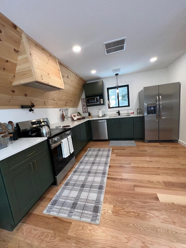 kitchen with sink, hanging light fixtures, stainless steel appliances, green cabinets, and light hardwood / wood-style floors