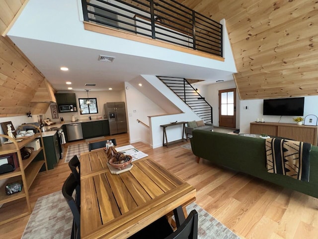 dining area with wooden walls, a towering ceiling, and light wood-type flooring