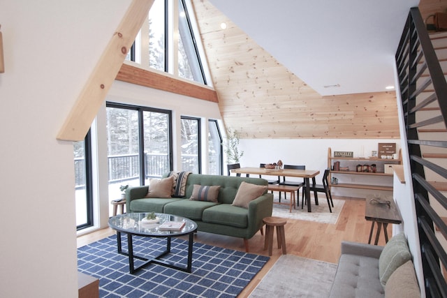 living room featuring wooden walls, light hardwood / wood-style flooring, and high vaulted ceiling