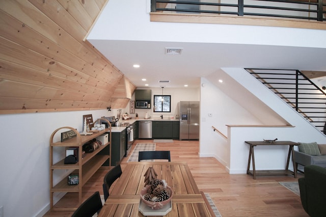 living room featuring wood walls, light wood-type flooring, and sink