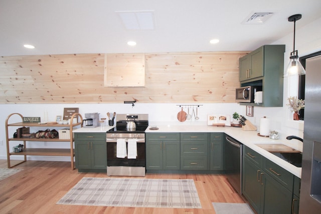 kitchen with pendant lighting, green cabinets, sink, light hardwood / wood-style flooring, and appliances with stainless steel finishes