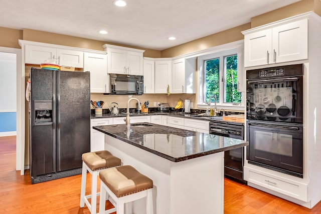 kitchen featuring black appliances, white cabinetry, sink, and light hardwood / wood-style floors