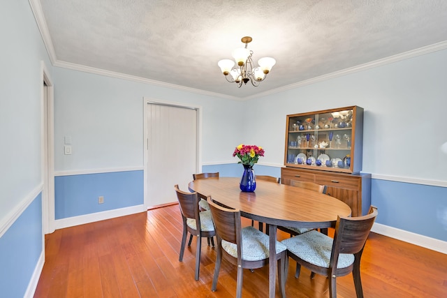 dining area with a chandelier, ornamental molding, dark hardwood / wood-style flooring, and a textured ceiling