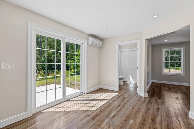 unfurnished room featuring hardwood / wood-style floors and a wall unit AC