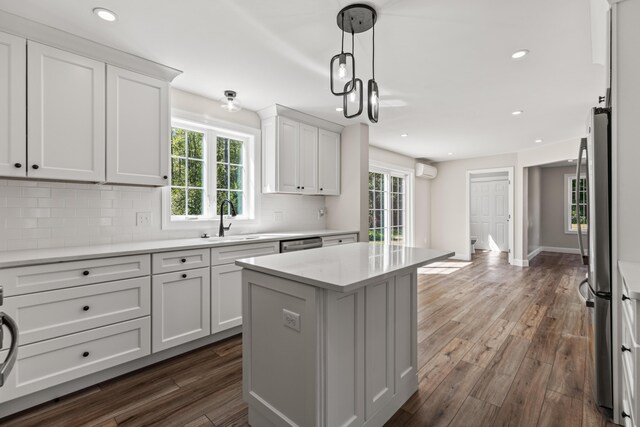 kitchen with a center island, dark hardwood / wood-style flooring, white cabinetry, and tasteful backsplash