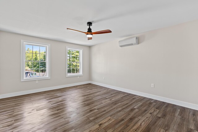 spare room featuring ceiling fan, a wall unit AC, and dark hardwood / wood-style flooring