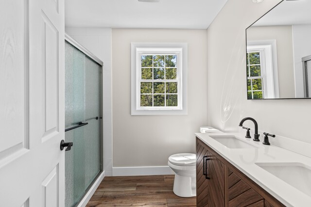 bathroom with toilet, a shower with door, hardwood / wood-style flooring, and vanity