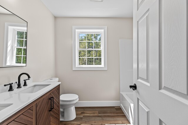 bathroom with vanity, toilet, a healthy amount of sunlight, and hardwood / wood-style flooring