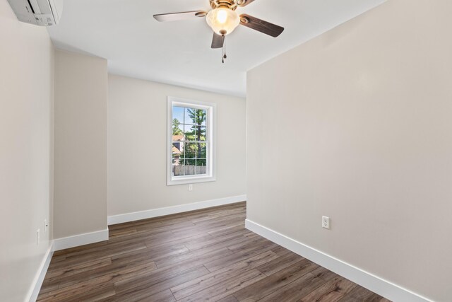 unfurnished room with ceiling fan, a wall unit AC, and dark hardwood / wood-style flooring