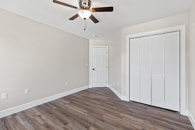 unfurnished bedroom with dark wood-type flooring, a closet, and ceiling fan