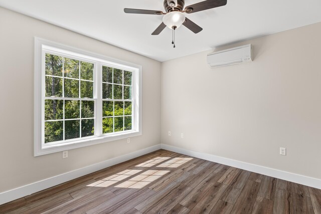 spare room featuring dark wood-type flooring, ceiling fan, and an AC wall unit