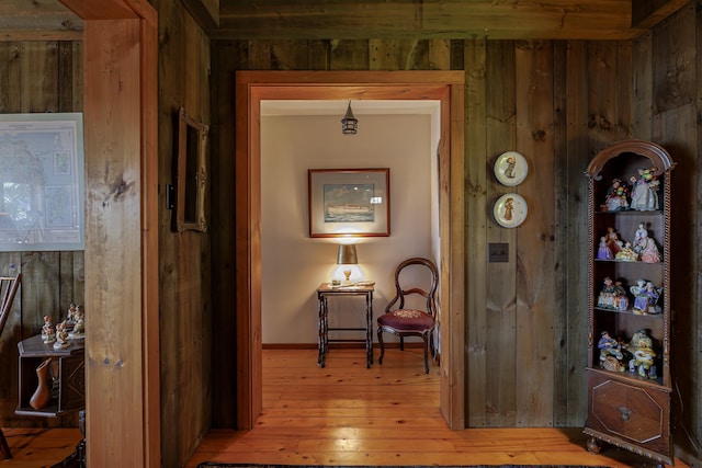 corridor with wooden walls, baseboards, and hardwood / wood-style floors