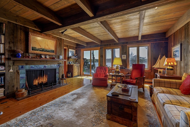 living area featuring wooden ceiling, a fireplace, wooden walls, and beamed ceiling