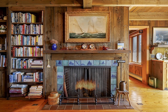 details with a fireplace with flush hearth, wooden walls, a baseboard heating unit, and wood finished floors