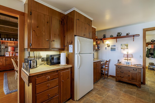 kitchen with brown cabinets, a toaster, light countertops, and freestanding refrigerator