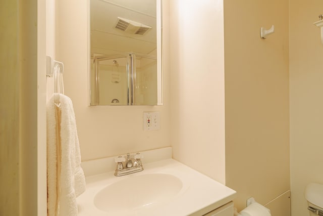 full bathroom with toilet, vanity, a shower stall, and visible vents