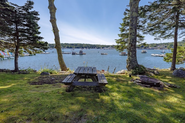 view of dock featuring a water view, an outdoor fire pit, and a yard