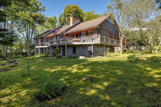 rear view of property featuring a lawn, a chimney, and a wooden deck