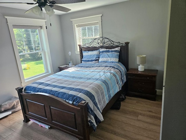 bedroom with ceiling fan, multiple windows, and hardwood / wood-style flooring