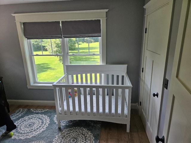 bedroom with a nursery area and hardwood / wood-style flooring