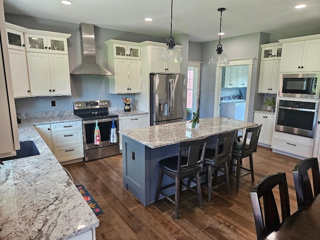 kitchen with stainless steel appliances, dark hardwood / wood-style flooring, a center island, and wall chimney exhaust hood