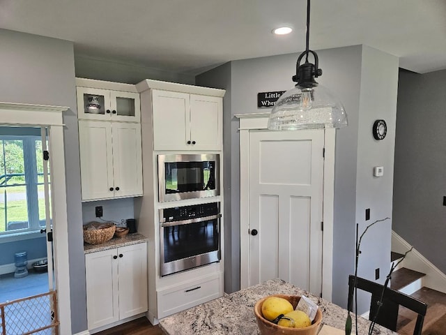 kitchen featuring appliances with stainless steel finishes, dark wood-type flooring, light stone countertops, and white cabinets