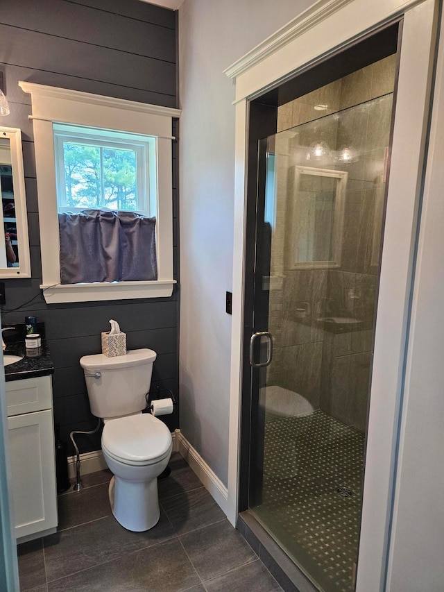 bathroom with a shower with door, toilet, tile patterned flooring, vanity, and tile walls