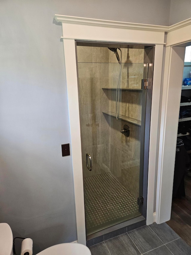 bathroom featuring hardwood / wood-style flooring, toilet, and a shower with door