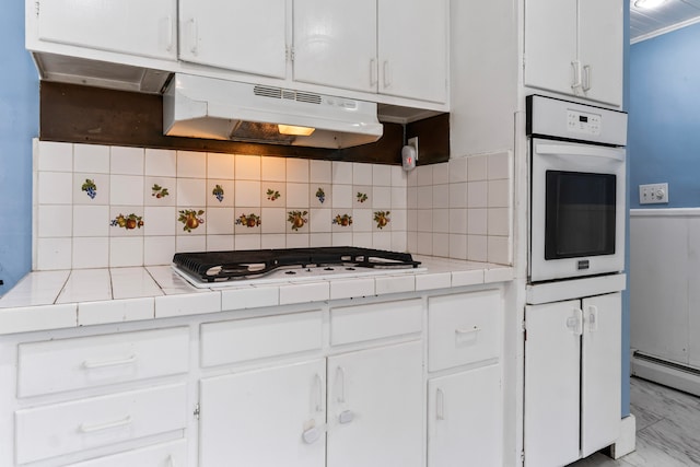 kitchen featuring decorative backsplash, white appliances, white cabinetry, and tile countertops