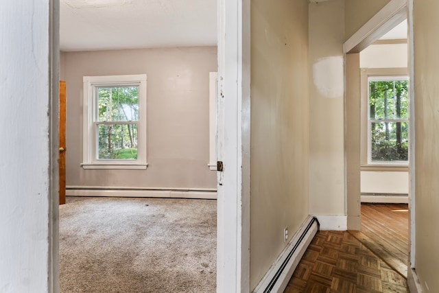 hallway with dark carpet and a baseboard heating unit