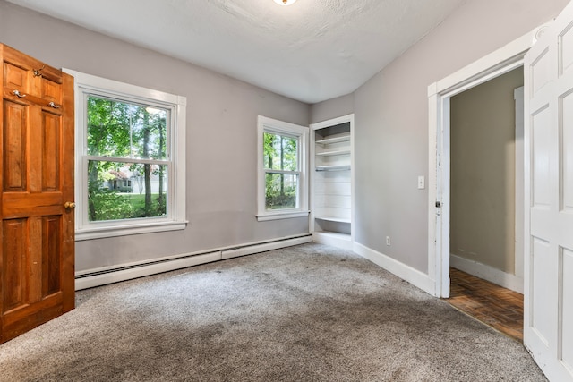 unfurnished bedroom featuring a textured ceiling, baseboard heating, carpet flooring, and multiple windows