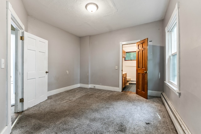 unfurnished bedroom with a textured ceiling, baseboard heating, and carpet flooring