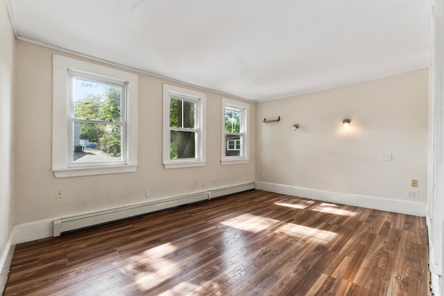 unfurnished room featuring a baseboard heating unit, a wealth of natural light, and dark hardwood / wood-style flooring