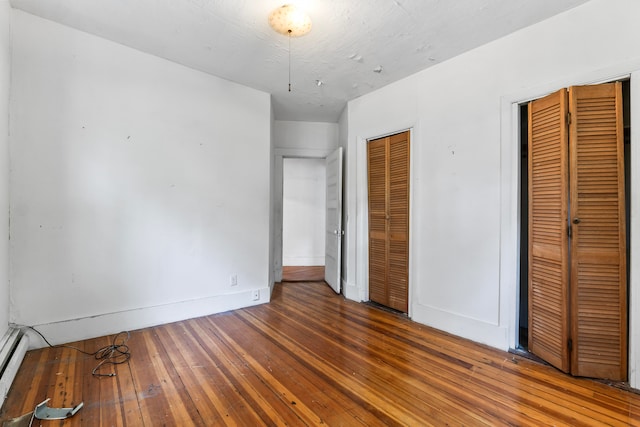 unfurnished bedroom with multiple closets and hardwood / wood-style flooring