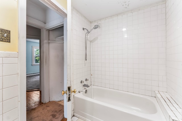 bathroom featuring wood-type flooring, a baseboard radiator, tile walls, and tiled shower / bath combo