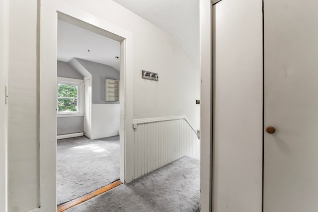 hall featuring light carpet, vaulted ceiling, and a baseboard heating unit