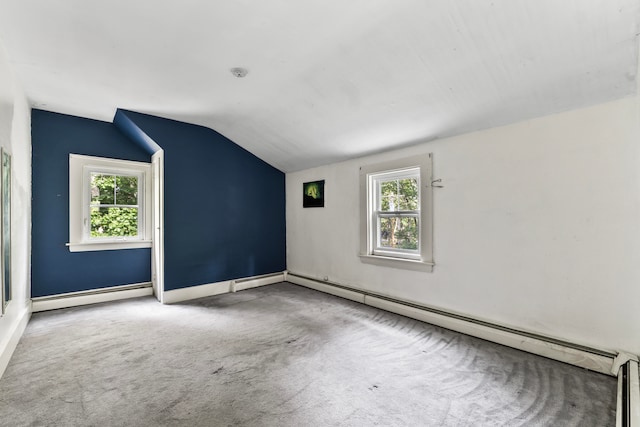 unfurnished room with plenty of natural light, vaulted ceiling, and a baseboard heating unit