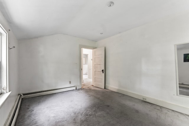 empty room featuring concrete flooring, baseboard heating, and lofted ceiling