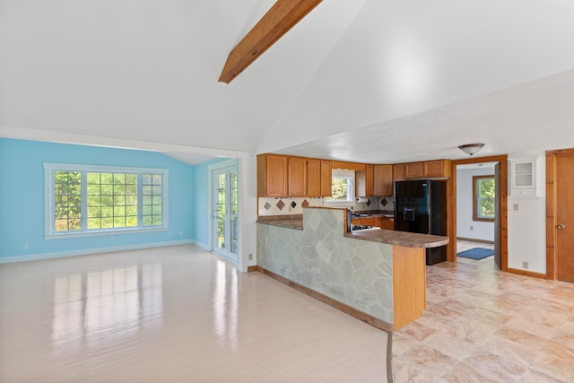 kitchen with lofted ceiling with beams, plenty of natural light, kitchen peninsula, and black fridge with ice dispenser