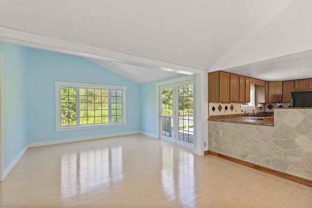 kitchen featuring light wood-type flooring, lofted ceiling, a healthy amount of sunlight, and black fridge