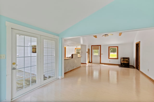 empty room with a wood stove, light wood-type flooring, and lofted ceiling