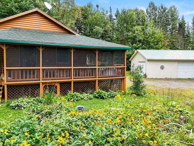 view of front of house featuring a sunroom, a garage, and an outbuilding