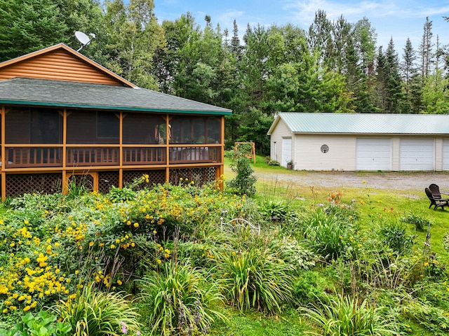 view of yard with a garage, a sunroom, and an outdoor structure