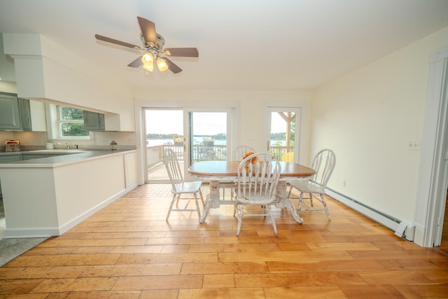 dining room with a baseboard heating unit, light hardwood / wood-style flooring, and a healthy amount of sunlight